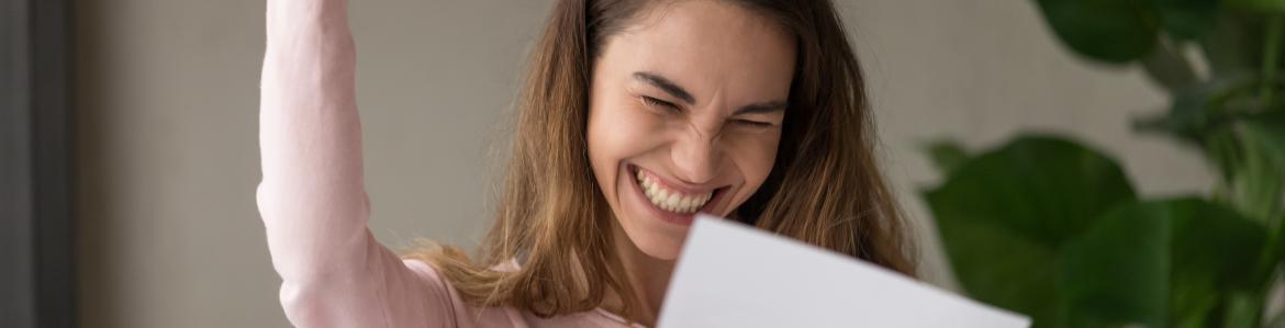 Becas para estudiantes universitarios Estudiante contenta leyendo una notificación
